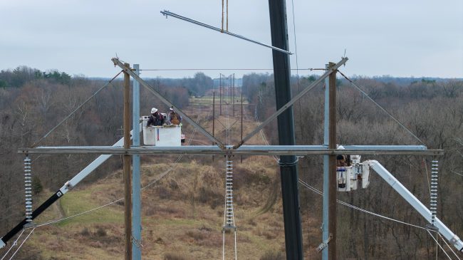 Hoosier Energy crew members work from bucket tracks nearly 100 feet in the air.