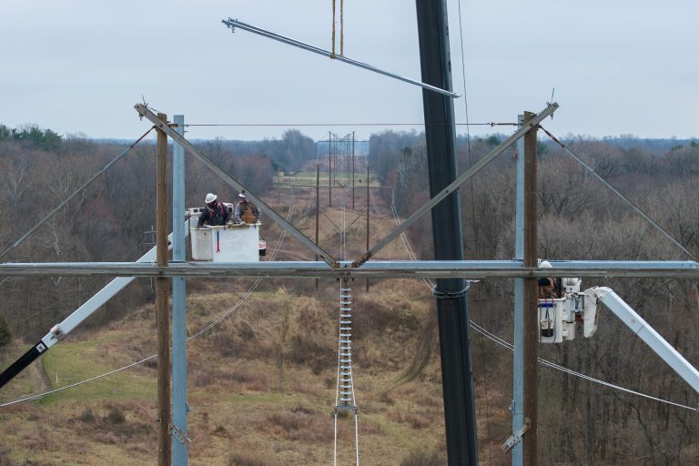 Hoosier Energy crew members work from bucket tracks nearly 100 feet in the air.